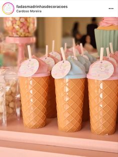 there are many ice creams in the cups on the table with candy sticks sticking out of them