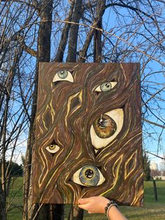 someone holding up a piece of art that looks like an eye in the tree trunk