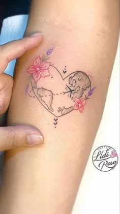 a woman's arm with a tattoo on it that has flowers in the shape of a heart