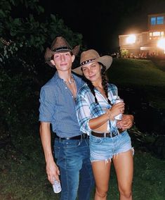 a man and woman standing next to each other in front of a house at night