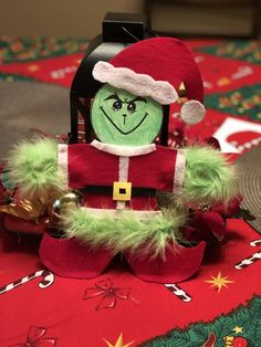 an elf doll sitting on top of a red table cloth covered in green and gold decorations