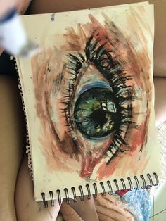 a woman holding a notebook with an eye drawn on it