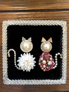 three pieces of jewelry are displayed on a black velvet box with bead trimmings