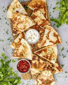 flatbread quesadillas on a cutting board with salsa, sour cream and parsley