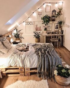 an attic bedroom is decorated in white and gray tones with string lights above the bed