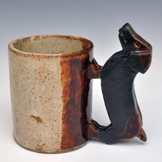 a brown and white mug with a small black squirrel on it's back legs