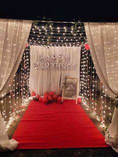 a red carpet and white curtains with lights on the wall behind it are decorated for a wedding