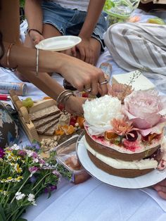 several people are gathered around a table with a cake on it and plates in front of them