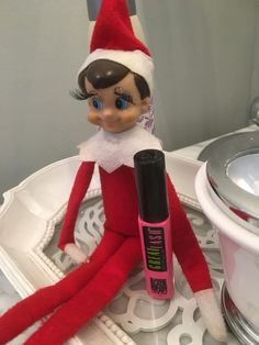 an elf is sitting on a tray next to a lip balm bottle and brush