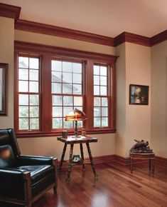 an empty living room with wood floors and two leather chairs in front of large windows