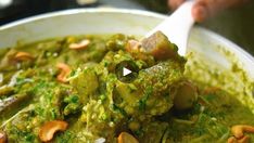 a white bowl filled with green food covered in pesto and cashew toppings