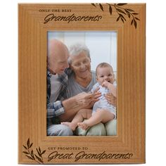 an old man and woman holding a baby in front of a wooden frame with the words grandparents