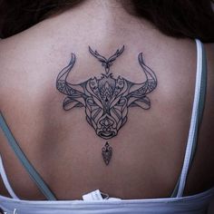 the back of a woman's neck with an intricate bull head tattoo on it