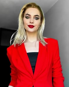 a woman in a red jacket and black dress with makeup on her face is posing for the camera