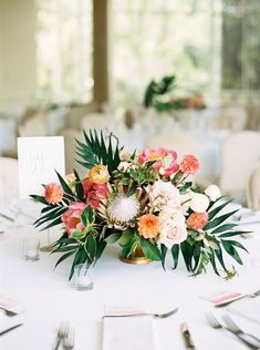 an arrangement of flowers and greenery on a table at a wedding reception with place cards