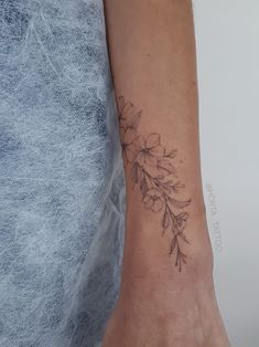 a woman's arm with a tattoo on it that has flowers in the middle