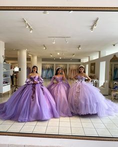 three women in dresses are standing in front of a mirror