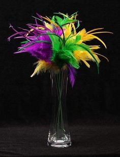 a glass vase filled with colorful flowers on top of a black table next to a wall