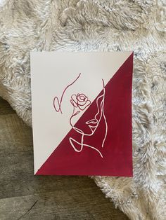 a piece of paper with a drawing of a woman's face on it next to a blanket