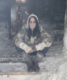 a woman sitting in the snow wearing a mask