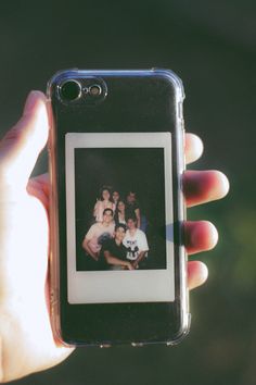 a person holding up a cell phone with an old photo on the front and back