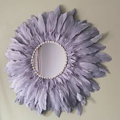 a mirror that is on the wall with some feathers hanging from it's sides