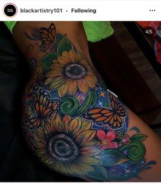 a woman's thigh with sunflowers and butterflies on her leg, while she is laying down