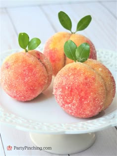 three peaches on a plate with leaves and sprinkles, ready to be eaten