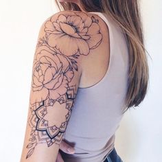 a woman's arm with flowers on it and a tattoo design on the upper half of her arm