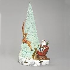 a small christmas tree with santa and reindeer on it's side, in front of a gray background