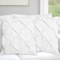 two white pillows sitting on top of a couch