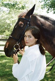 a woman standing next to a brown horse