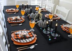 the table is set for halloween dinner with black and orange plates