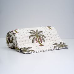 a white blanket with a palm tree design on the front and bottom, rolled up