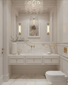 a white bathroom with a chandelier hanging from the ceiling and marble counter tops