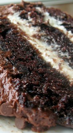 a close up of a piece of cake on a plate with chocolate and white frosting