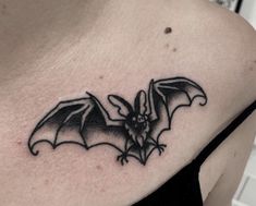 a black and white photo of a bat tattoo on the back of a woman's shoulder