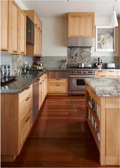 a kitchen with wooden cabinets and stainless steel appliances, along with hardwood flooring that matches the walls