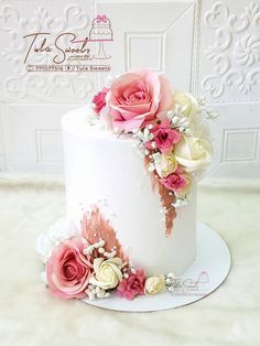 there is a white cake with pink and white flowers on it