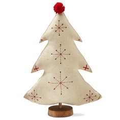 a small white christmas tree on a wooden stand with red balls and snowflakes