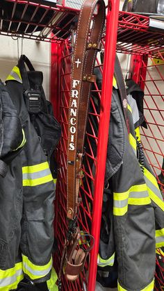 two fire fighters standing next to each other in front of red racks with harnesses on them