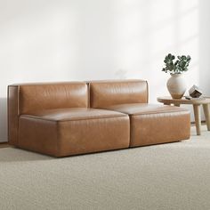 a brown leather couch sitting on top of a carpeted floor next to a table