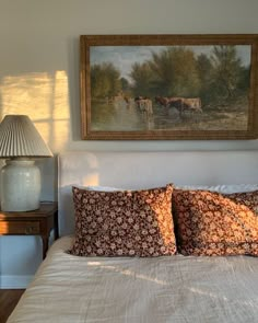 a bedroom with a painting on the wall above it and a bed with two pillows