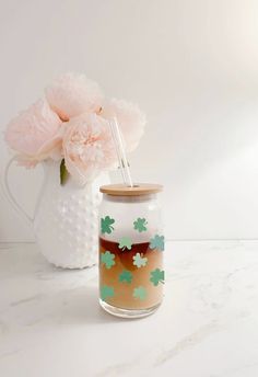 a vase with flowers in it sitting on a table next to a glass jar filled with liquid