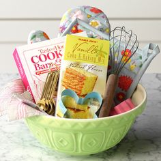 a green bowl filled with lots of cooking utensils and cookbooks on top of a table