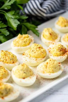 deviled eggs with mustard sprinkled on them are sitting on a white plate