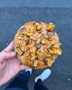 a person holding up a pastry with nuts on it