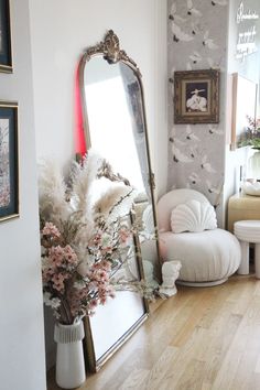 a mirror sitting on top of a wooden floor next to a white chair and table