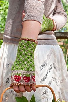 a woman is holding a basket with flowers in it and her hands are knitted