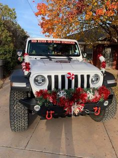 a jeep decorated for christmas with decorations on the hood and front bumper, is parked in a driveway